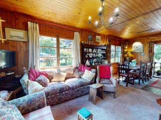 Step into this charming living and dining area, featuring warm wood paneling and a cozy floral sofa perfect for relaxation.