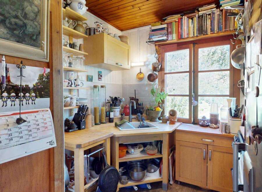 Charming rustic kitchen featuring warm wooden cabinetry and ceiling, complemented by a functional layout with ample counter space and open shelving.