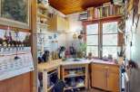 Charming rustic kitchen featuring warm wooden cabinetry and ceiling, complemented by a functional layout with ample counter space and open shelving.