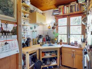 Charming rustic kitchen featuring warm wooden cabinetry and ceiling, complemented by a functional layout with ample counter space and open shelving.