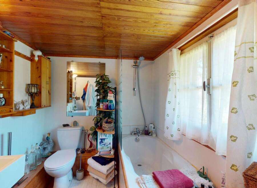 Discover a charming bathroom featuring a classic white toilet and a spacious bathtub, perfect for relaxation.