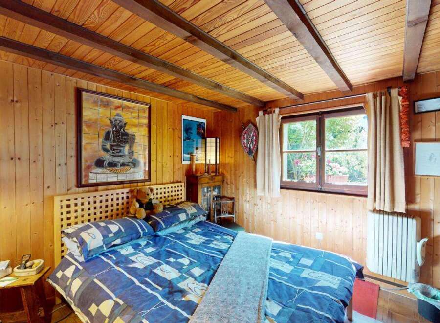 Experience rustic charm in this cozy bedroom featuring warm wood paneling and a slatted headboard.