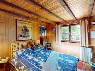 Experience rustic charm in this cozy bedroom featuring warm wood paneling and a slatted headboard.