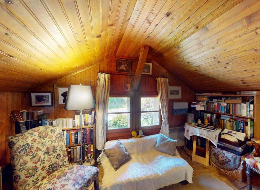 Cozy attic living space featuring warm wood paneling and a vaulted ceiling.