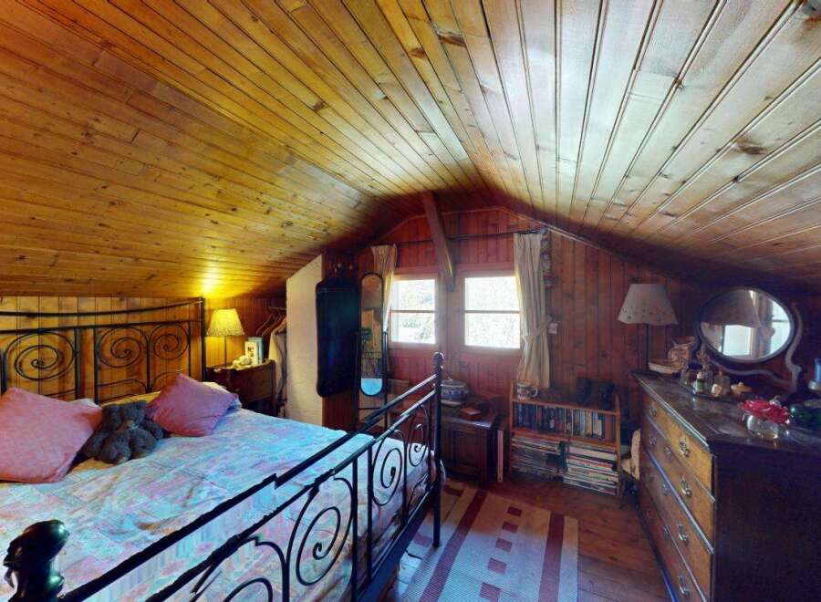 Step into this charming rustic bedroom featuring a cozy wooden ceiling and walls, creating a warm and inviting atmosphere.