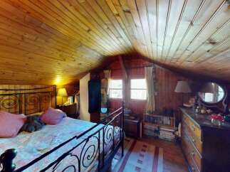 Step into this charming rustic bedroom featuring a cozy wooden ceiling and walls, creating a warm and inviting atmosphere.