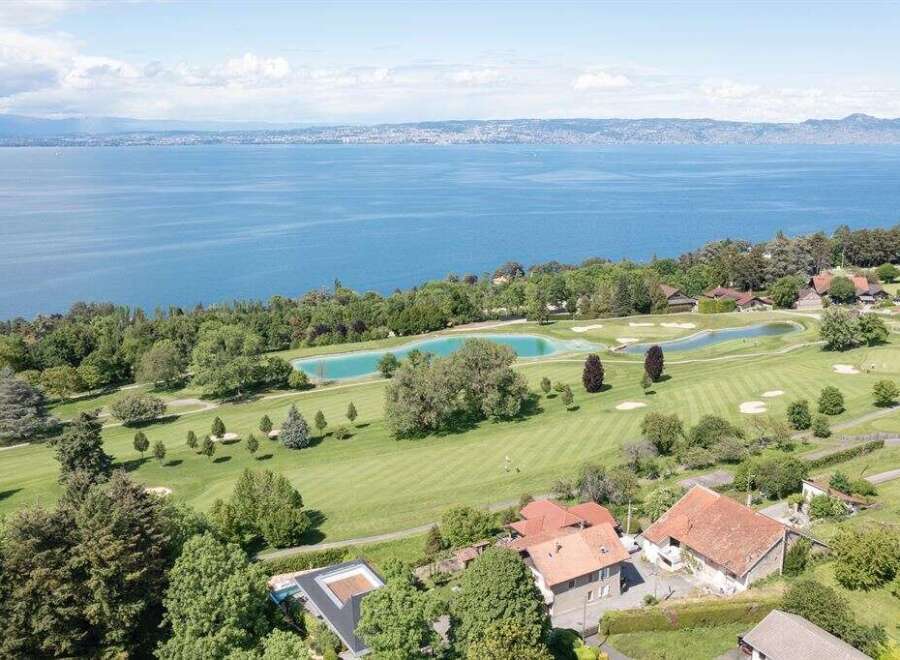 Experience luxury living with this stunning aerial view of a property nestled beside a pristine golf course and a tranquil lake.