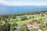 Experience luxury living with this stunning aerial view of a property nestled beside a pristine golf course and a tranquil lake.