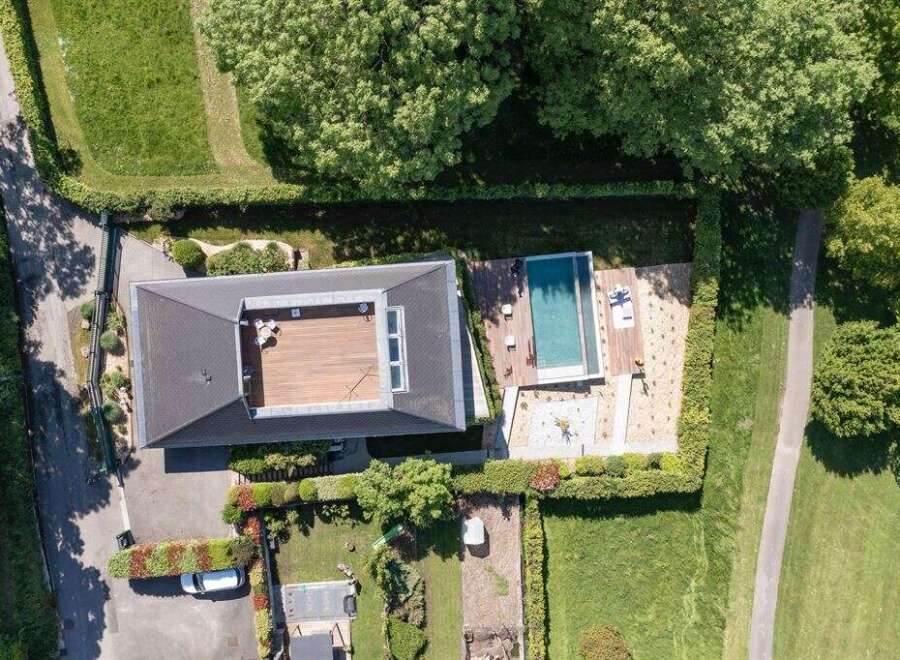 Experience modern luxury with this stunning aerial view of a property featuring a sleek, contemporary home with a spacious rooftop deck.