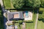 Experience modern luxury with this stunning aerial view of a property featuring a sleek, contemporary home with a spacious rooftop deck.