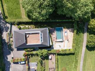 Experience modern luxury with this stunning aerial view of a property featuring a sleek, contemporary home with a spacious rooftop deck.