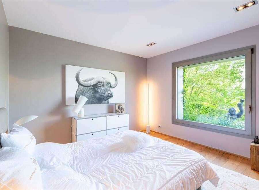 Experience modern comfort in this serene bedroom, featuring a striking buffalo artwork above a sleek dresser.