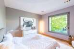 Experience modern comfort in this serene bedroom, featuring a striking buffalo artwork above a sleek dresser.