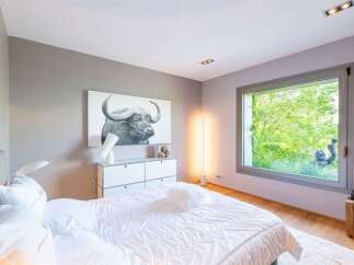 Experience modern comfort in this serene bedroom, featuring a striking buffalo artwork above a sleek dresser.