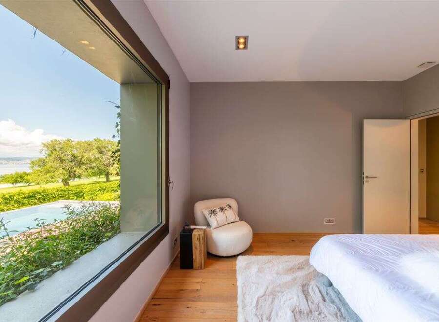 Experience luxurious living with this stunning bedroom featuring a large picture window that offers breathtaking views of the surrounding landscape and a serene pool.