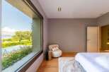 Experience luxurious living with this stunning bedroom featuring a large picture window that offers breathtaking views of the surrounding landscape and a serene pool.