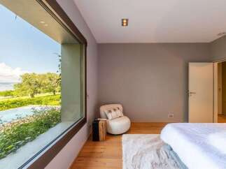 Experience luxurious living with this stunning bedroom featuring a large picture window that offers breathtaking views of the surrounding landscape and a serene pool.