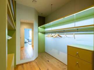 Step into this modern walk-in closet, featuring sleek, built-in shelving with integrated LED lighting for a sophisticated ambiance.