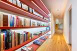 This hallway features a striking modern design with vibrant red shelving units illuminated by subtle LED lighting, creating a warm and inviting ambiance.