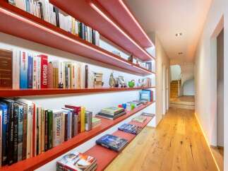 This hallway features a striking modern design with vibrant red shelving units illuminated by subtle LED lighting, creating a warm and inviting ambiance.