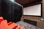 Experience cinematic bliss in this state-of-the-art home theater, featuring plush orange seating and a massive projection screen for an immersive viewing experience.