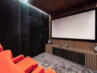 Experience cinematic bliss in this state-of-the-art home theater, featuring plush orange seating and a massive projection screen for an immersive viewing experience.