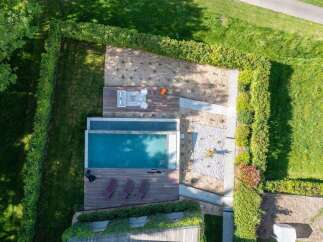 Experience luxury outdoor living with this stunning property featuring a sleek infinity pool and expansive wooden deck.