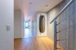 Experience modern living in this stunning hallway featuring a sleek metal handrail against a textured concrete wall.