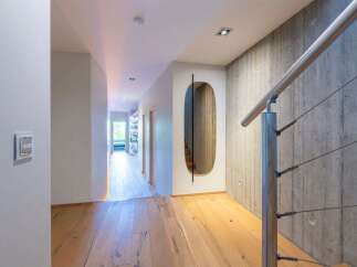 Experience modern living in this stunning hallway featuring a sleek metal handrail against a textured concrete wall.