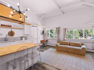 Discover this bright and airy living space, featuring a modern kitchen with a butcher block island and sleek white cabinetry.