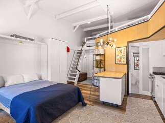 Discover this charming studio apartment featuring a space-saving Murphy bed and a convenient loft area accessible by stairs.