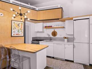 This modern kitchen features a sleek white cabinetry, a stainless steel gas range, and a spacious butcher block island perfect for meal prep.