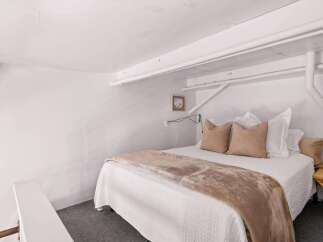 Discover this charming bedroom featuring a comfortable queen-size bed adorned with plush pillows and a soft throw blanket.