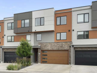Discover modern living in this stunning townhouse featuring a striking facade with a mix of wood-grain siding, stone accents, and sleek grey panels.