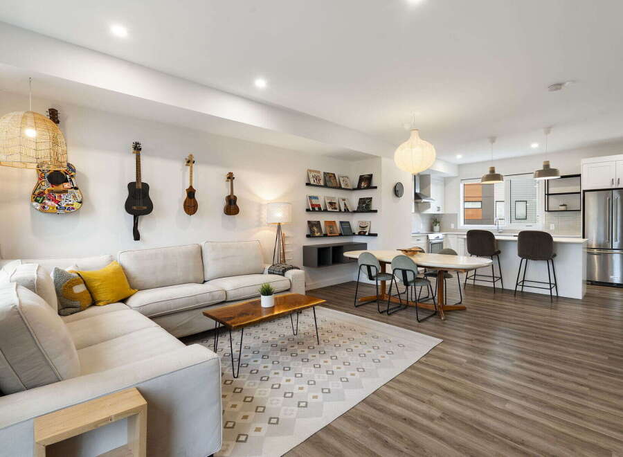 This open-concept living space features a comfortable sectional sofa adorned with decorative pillows, complemented by a stylish coffee table and a geometric rug.