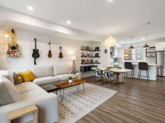 This open-concept living space features a comfortable sectional sofa adorned with decorative pillows, complemented by a stylish coffee table and a geometric rug.