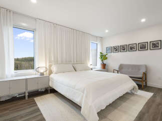Experience modern comfort in this serene bedroom, featuring a plush white duvet and a minimalist aesthetic.