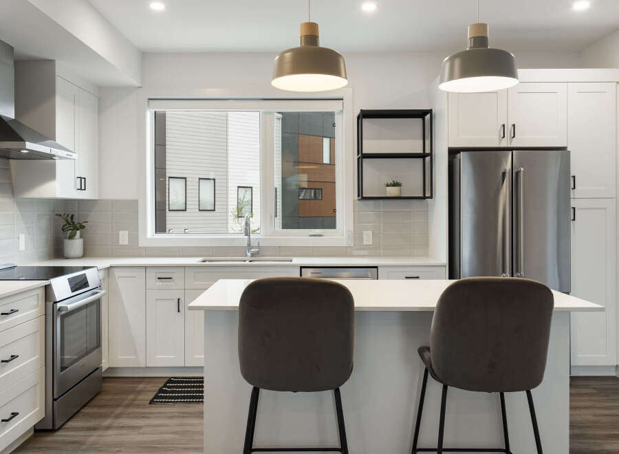 Experience modern living in this stunning kitchen, featuring sleek white cabinetry, a spacious island with bar seating, and top-of-the-line stainless steel appliances.