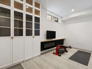 This modern home gym features a sleek white built-in cabinet with glass doors, perfect for storing workout gear.
