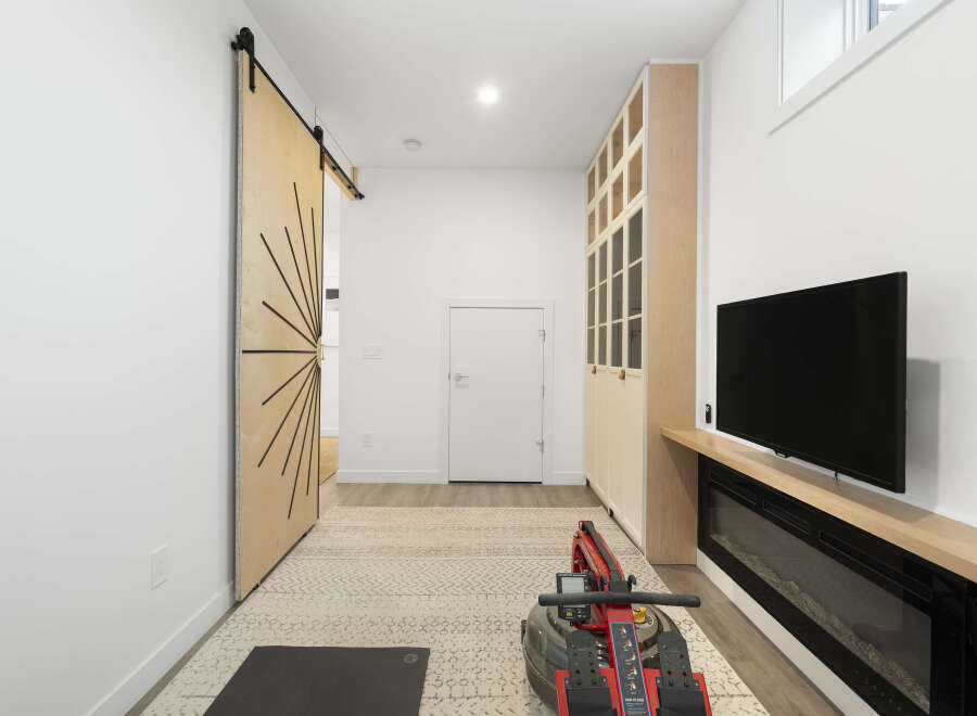 This modern living space features a stylish barn door leading to an open hallway, complemented by a large built-in cabinet for ample storage.