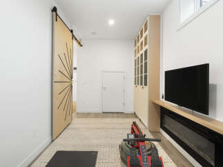 This modern living space features a stylish barn door leading to an open hallway, complemented by a large built-in cabinet for ample storage.