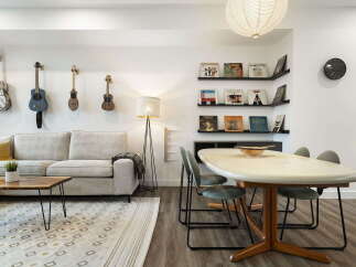 This stylish living and dining area features a comfortable cream sofa adorned with a plaid throw, complemented by a live-edge coffee table and a geometric rug.