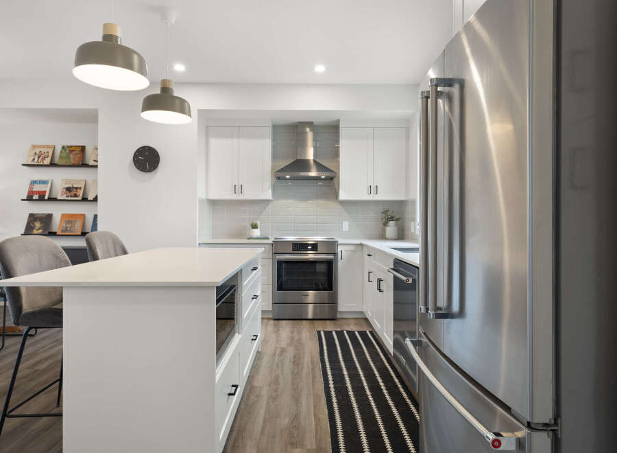 Experience modern living in this stunning kitchen, featuring sleek white cabinetry, a stainless steel range, and a spacious island perfect for meal prep and casual dining.