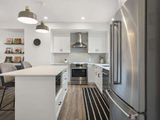 Experience modern living in this stunning kitchen, featuring sleek white cabinetry, a stainless steel range, and a spacious island perfect for meal prep and casual dining.