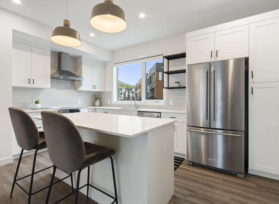 Experience modern living in this stunning kitchen, featuring sleek white cabinetry, a spacious island with bar seating, and a large window offering picturesque views.