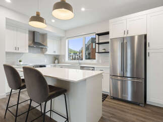 Experience modern living in this stunning kitchen, featuring sleek white cabinetry, a spacious island with bar seating, and a large window offering picturesque views.