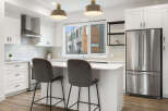 Experience modern living in this stunning kitchen, featuring sleek white cabinetry, a stainless steel range hood, and a spacious island perfect for casual dining.