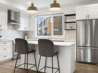 Experience modern living in this stunning kitchen, featuring sleek white cabinetry, a stainless steel range hood, and a spacious island perfect for casual dining.