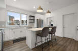 Experience modern living in this stunning kitchen featuring sleek white cabinetry, a spacious island with bar seating, and elegant pendant lighting.