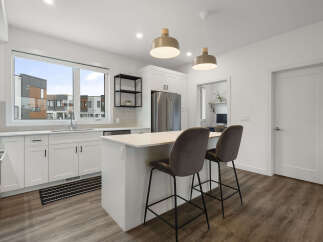 Experience modern living in this stunning kitchen featuring sleek white cabinetry, a spacious island with bar seating, and elegant pendant lighting.
